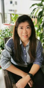 Yuni Yapidin in vertical striped shirt surrounded by plants.